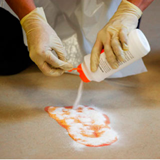 photo of a technician using absorbent powders on a table top spill