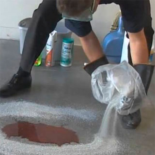 photo of a factory worker using absorbent powder on a floor spill